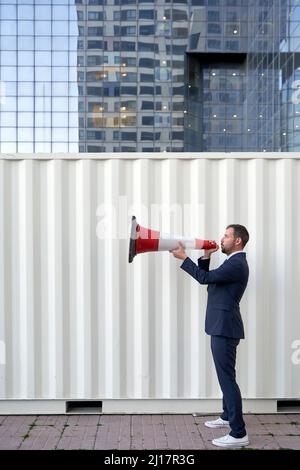 Un uomo d'affari gridando attraverso il megafono sul sentiero della città Foto Stock