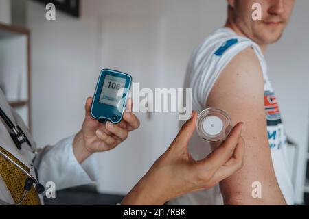 Medico che misura la glicemia del paziente in clinica Foto Stock