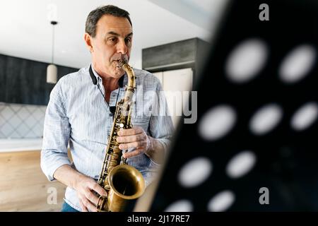 Sassofonista che pratica il sassofono a casa Foto Stock