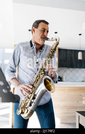 Sassofonista con occhi chiusi giocando sassofono a casa Foto Stock