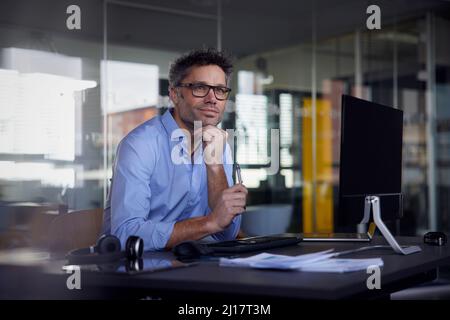 Uomo d'affari premuroso seduto con la mano sul mento alla scrivania ufficio Foto Stock