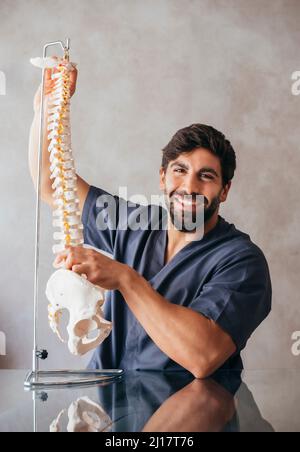 Fisioterapista sorridente che tiene il modello della spina umana Foto Stock