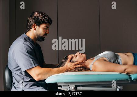 Fisioterapista che dà il massaggio della testa alla donna in clinica medica Foto Stock