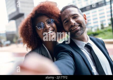 Due colleghi di lavoro che prendono selfie all'aperto Foto Stock