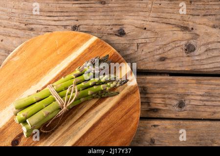 Direttamente sopra la vista del mazzo di verdure di asparagi crudi legato a corda sul tagliere di legno sopra il tavolo Foto Stock