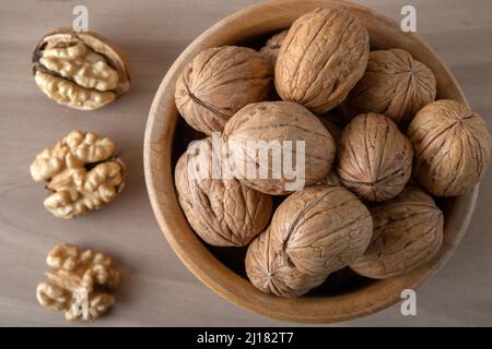 Noci pelate e noci intere su sfondo di legno Foto Stock