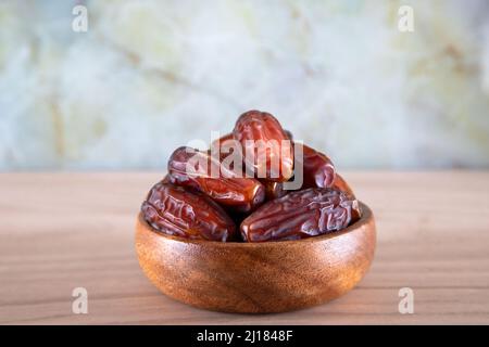 Ciotola di frutta di data su sfondo di legno Foto Stock