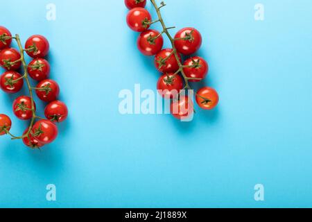 Vista dall'alto di pomodori freschi di ciliegia rossa ramoscelli su sfondo blu con spazio copia Foto Stock