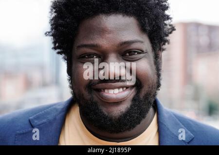 African curvy Happy uomo sorridendo sulla macchina fotografica all'aperto - Focus on Face Foto Stock