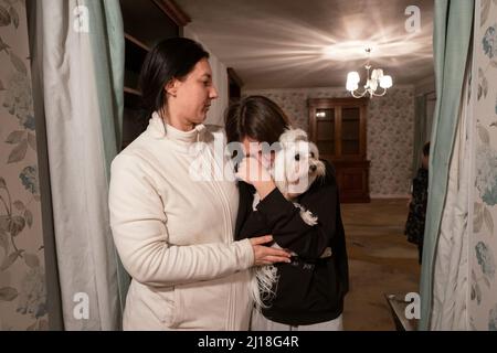 RITRASMESSO CON LA CORRETTA ORTOGRAFIA DI REND PLATINGS Valeria Starkova e sua figlia Kamila con il loro cane Florie, nella loro nuova casa a Caldecote vicino a Cambridge. La famiglia di dieci, che ha un'età compresa tra Alikhan, di 10 anni, e la nonna Ludmila, di 90 anni, ha iniziato i loro viaggi il 1 marzo, e sono stati aiutati da Rend platings a trovare una nuova casa nel Regno Unito per loro e i loro due cani Mikki e Florie. Data foto: Martedì 22 marzo 2022. Foto Stock