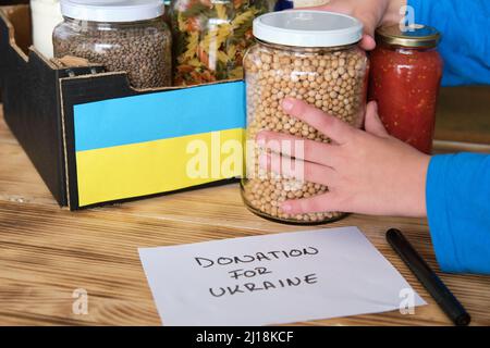 Una persona che prepara una scatola con cibo da donare alla guerra in Ucraina. Foto Stock