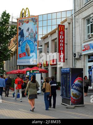 Chisinau o Kishinev, Moldavia: Vista del centro di Chisinau con la gente su un marciapiede. Pedoni su una strada fuori dal McDonald's a Chisinau. Foto Stock