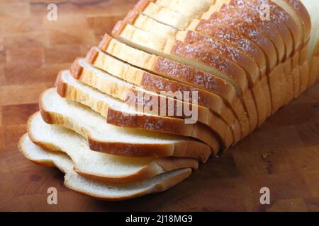 Pane bianco al latte affettato su sfondo di legno Foto Stock