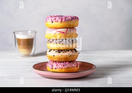 Ciambelle decorate con vetri su piatti e latte di caffè o cappuccino Foto Stock
