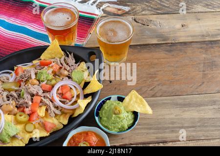 Vassoio in ceramica nera di nachos con ciotole di salsa di carne e birra con decorazioni messicane. Ciotole di salsa. Spazio di copia. Cucina messicana. Foto Stock