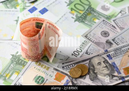 Moneta diversa in banconote da 100 euro, 100 dollari e vortice russo rublo. Primo piano. Dollari americani o dollari americani Foto Stock