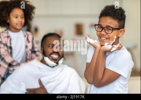 Ragazzo che guarda la fotocamera che tocca il volto con la schiuma Foto Stock