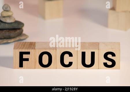 Uomo d'affari con segno Focus scritto su blocchi di legno bianco sul tavolo di fronte a lui. Foto Stock