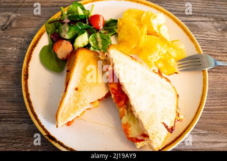 Pranzo in un caffè del North Yorkshire country con formaggio e panino tostato con peperoni su pane bianco con insalata e patatine Foto Stock