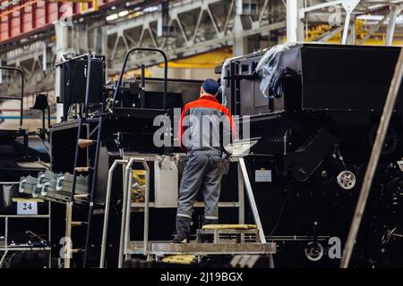 I lavoratori industriali assemblano la trebbiatrice agricola in officina. Foto Stock