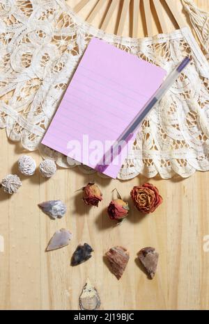 Notepaper su Vintage Lace Fan con rose secche e frecce native americane su sfondo di legno Foto Stock