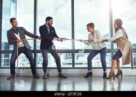 Ci sono molte sfide che youll devono affrontare nel commercio. Fucilato di un gruppo di uomini d'affari che tirano su una corda durante il rimorchiatore di guerra in un ufficio. Foto Stock