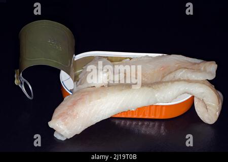 Filetti di merluzzo atlantico (Gadus morhua), skrei, giacente in una lattina di alluminio aperta, fotografia studio con sfondo nero Foto Stock