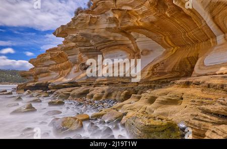Immagine a lunga esposizione con acqua di mare sfocata al sole delle Painted Cliffs, una formazione geologica rocciosa a motivi marini, Maria Island, Tasmania, Australia Foto Stock