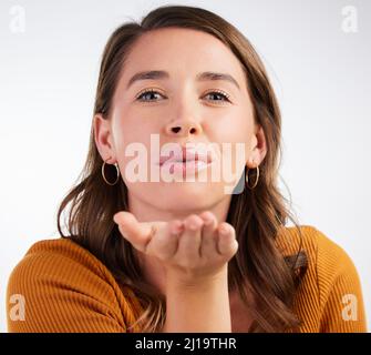 Inviare un po 'di amore a modo tuo. Studio girato di una giovane donna che soffia un bacio su uno sfondo bianco. Foto Stock