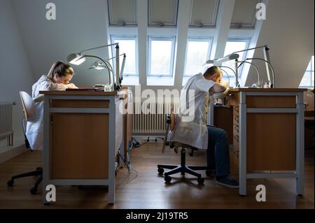 25 febbraio 2022, Sassonia, Glashütte: I produttori di orologi siedono in produzione presso la fabbrica di orologi Nomos. Con il marchio di protezione per orologi da Glashütte, una nuova era è all'alba per il totale di dieci manifatture. Foto: Sebastian Kahnert/dpa-Zentralbild/dpa Foto Stock