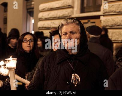 Una donna anziana che partecipa alle processioni notturne del Venerdì Santo a Trapani, in Sicilia, Italia Foto Stock