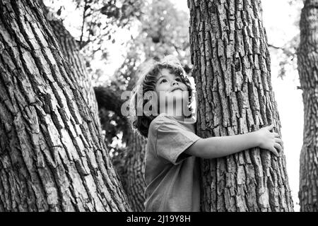 Ragazzo giovane abbracciando un ramo di albero. Ragazzino su un ramo di albero. Il bambino sale su un albero. Foto Stock