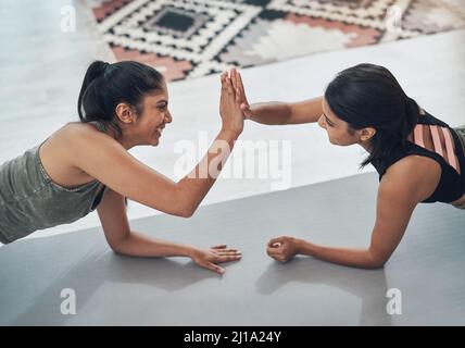 Più ci motiviamo a vicenda, meglio facciamo. Scatto di due belle giovani donne che si esercitano insieme a casa. Foto Stock