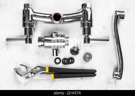 fondo idraulico - vista sopra chiave, valvola del rubinetto della doccia smontata, deviatore, beccuccio, guarnizioni su asse di calcestruzzo Foto Stock