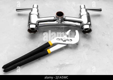 impianto idraulico ancora vita - chiave vicino a rubinetto doccia disassemblato valvola su asse di calcestruzzo Foto Stock