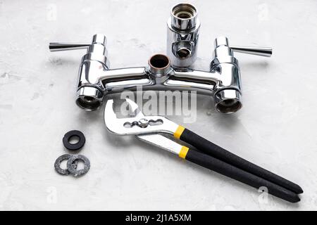 impianto idraulico ancora vita - chiave, guarnizioni quasi smontate rubinetto doccia con deviatore su asse di calcestruzzo Foto Stock