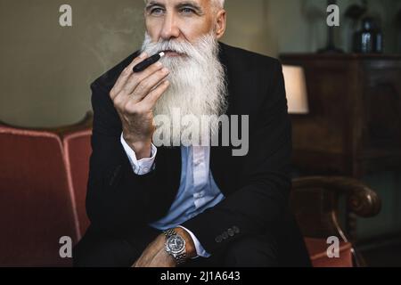 Bell'uomo anziano fumare tabacco riscaldamento sistema Foto Stock
