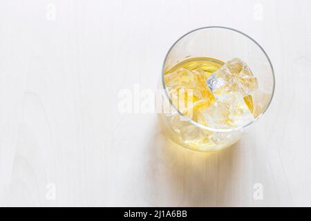 sopra la vista della porzione di whisky scotch di malto singolo sulle rocce in vetro su tavolo pallido con copyspace Foto Stock