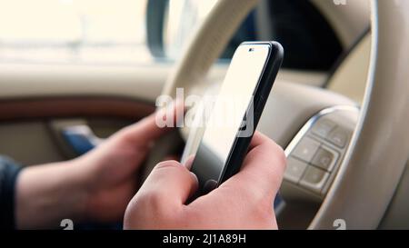 La mano di Mans tiene il telefono e tocca lo schermo in un'auto. Utilizzando il telefono e guarda il percorso sulle mappe come arrivare al luogo desiderato. Viaggi Foto Stock