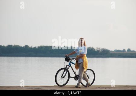Donna di mezza età con bicicletta sulla riva del lago in Serbia Foto Stock