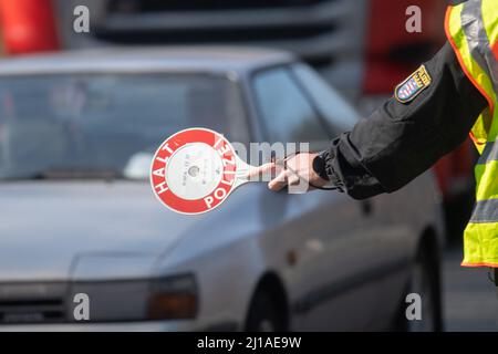 24 marzo 2022, Hessen, Francoforte sul meno: Un poliziotto ferma un'auto con una siviera che dice "polizia di arresto" a un checkpoint per la giornata di azione stradale della 'Spedmarathon'. Oggi si sta svolgendo una giornata di controllo a livello europeo, durante la quale si stanno prendendo di mira soprattutto i conducenti che accelerano. Foto: Sebastian Christoph Gollnow/dpa Foto Stock