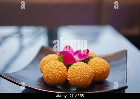 Palle di sesamo croccanti fritte come dessert su piatto nero Foto Stock