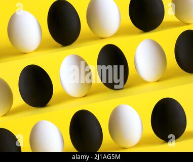 Uova bianche e nere su sfondo giallo. Foto Stock