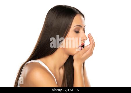 una giovane donna controlla il respiro con il palmo su sfondo bianco Foto Stock