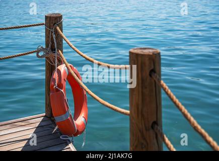 Lifbuoy arancione sul molo di legno. Bel tempo soleggiato Foto Stock