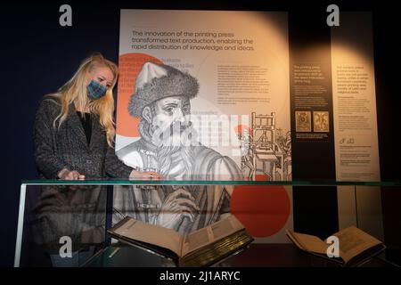 Edimburgo. Scozia, Regno Unito. 24th Mar 2022. La Biblioteca Nazionale di Scozia mostra in casi come Timothy PontÕs carte rivoluzionarie, effetti del pioniere Isobel Wylie Hutchison, Charles DarwinÕs sull'origine della specie, una lettera di Ludwig van Beethoven, ScotlandÕs prime stampanti Chepman & Myllar, una Bibbia Gutenberg completa, prime edizioni internazionali di Harry Potter, E Robert BurnsÕs AE Fond Kiss. Nuova mostra chiamata: Tesori della Biblioteca Nazionale di Scozia. Nella foto: Sarah Drummond dal dipartimento PR pose la prossima Bibbia di Gutenberg. Credit: Pako Mera/Alamy Live News Foto Stock