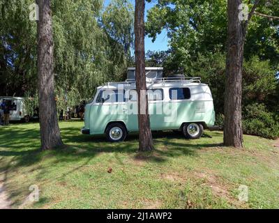 Vecchio pulmino bianco Volkswagen tipo 2 T2 Camper Kombi parcheggiato sull'erba dietro gli alberi. Mostra auto classica Suda VW. CopySpace Foto Stock