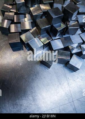 pila di piccoli cubi in acciaio lucido lavorato a macchina su superficie metallica Foto Stock