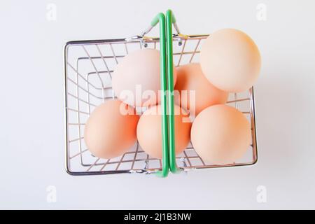 Uova di pollo in un carrello. Uova nel deposito. Cibo fresco sulla mensola. Cestino di cibo. Primo piano su uno sfondo bianco dall'alto. Foto Stock