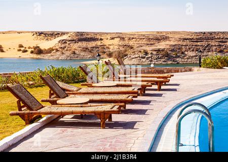 Fila di sedie a sdraio per la piscina con vista sul lago Nasser presso il villaggio di Abu Simbel, Assuan, Alto Egitto. Foto Stock